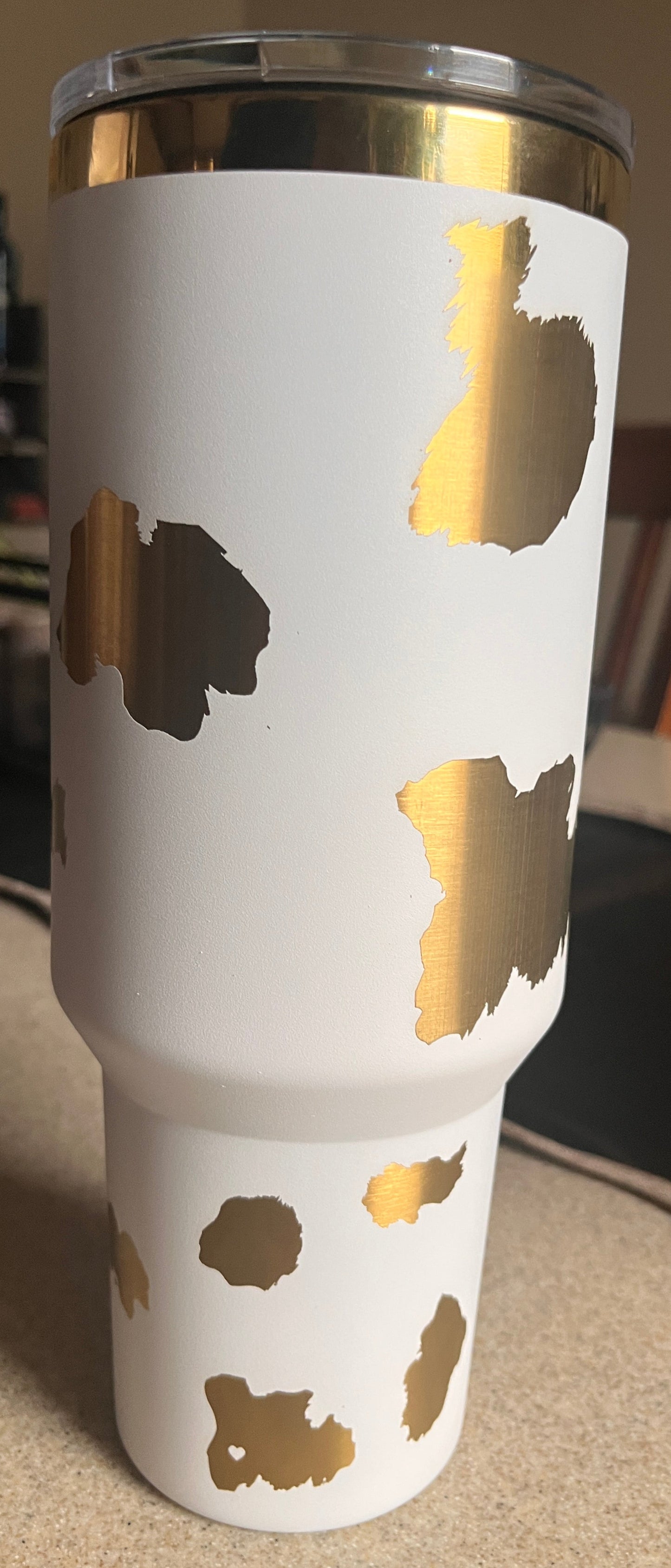 White tumbler with gold cow print design on a blurred background