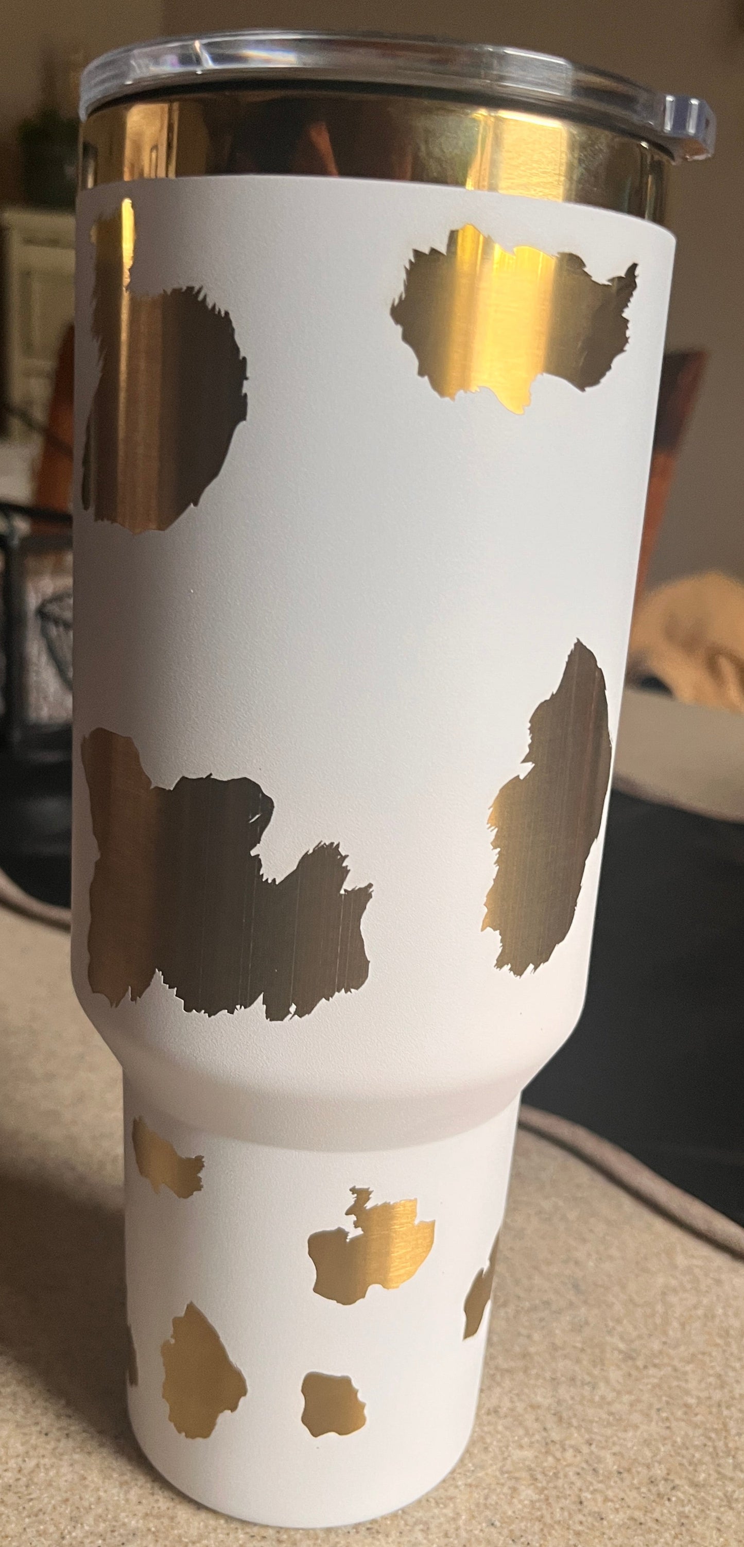 White tumbler with gold leaf pattern on a blurred background