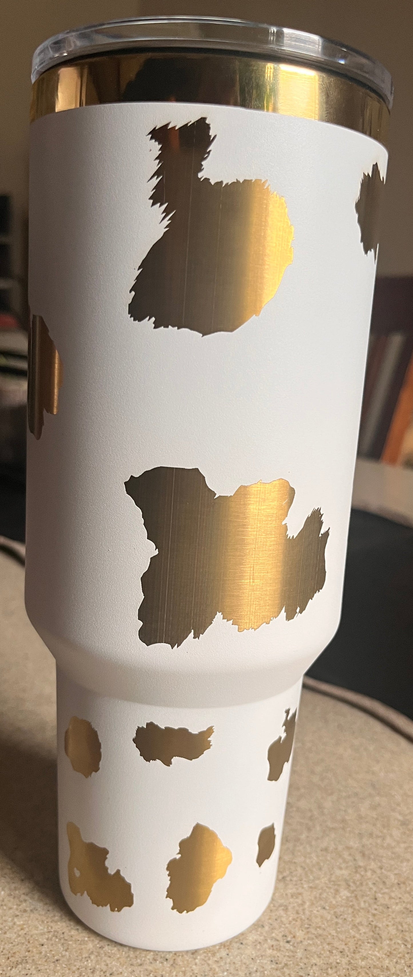 White tumbler with gold designs on a blurred background