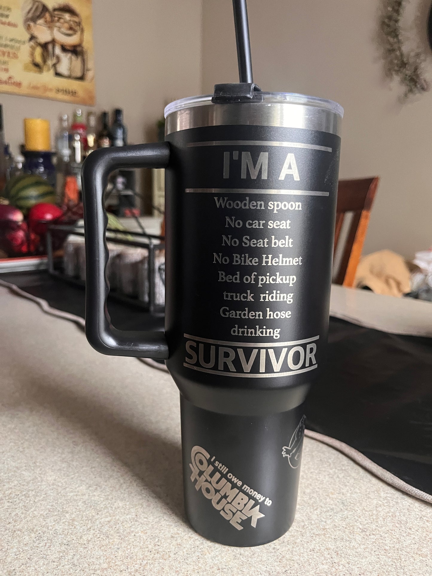 Black and silver thermos with 'I'm a Survivor' text on a blurred background