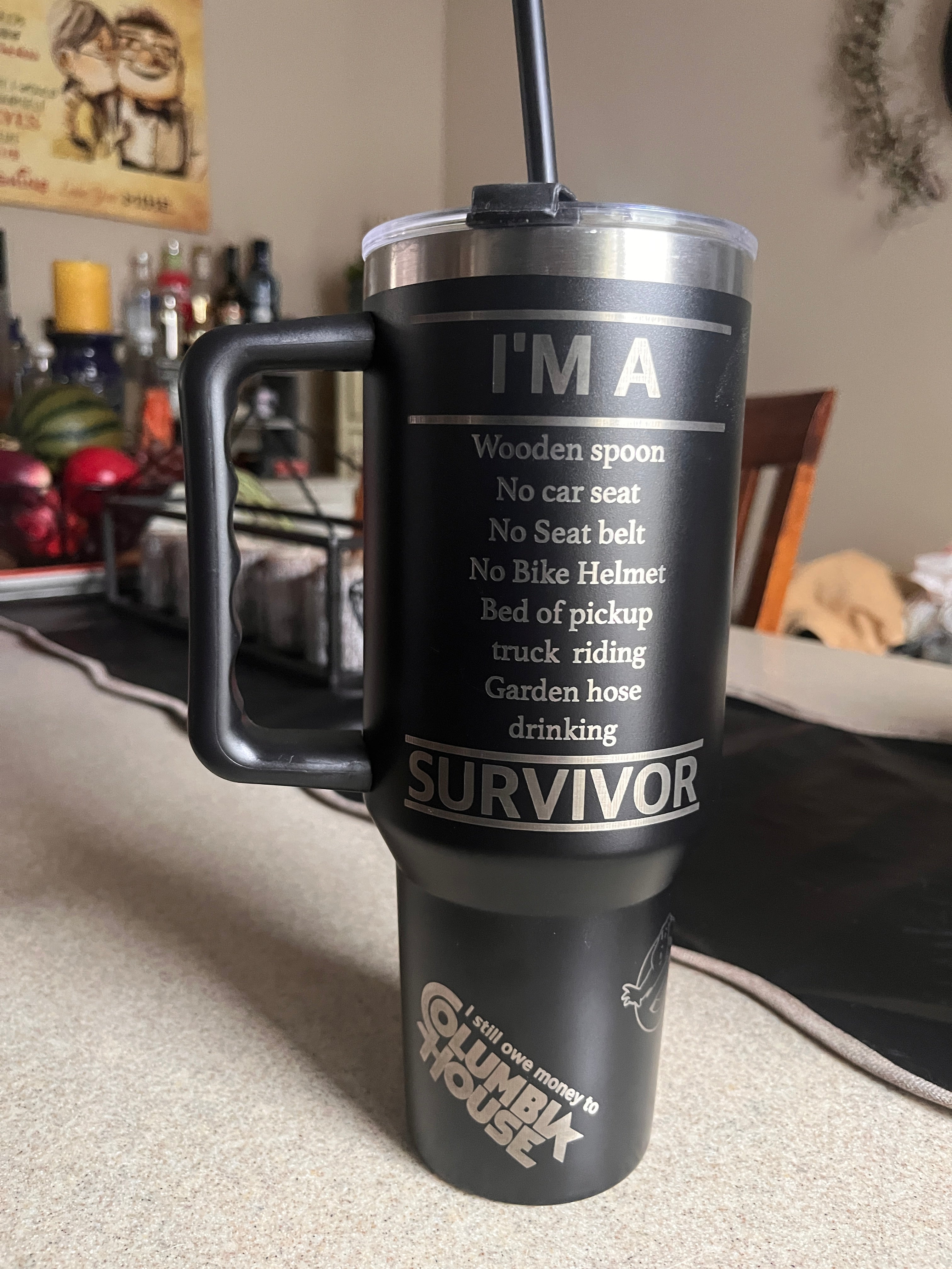 Black and silver thermos with 'I'm a Survivor' text on a blurred background